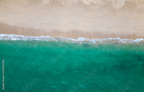 Aerial drone view (top down) to sea waves and white sand. Turquoise blue water, tropical theme. Concept of relaxation in pure nature.