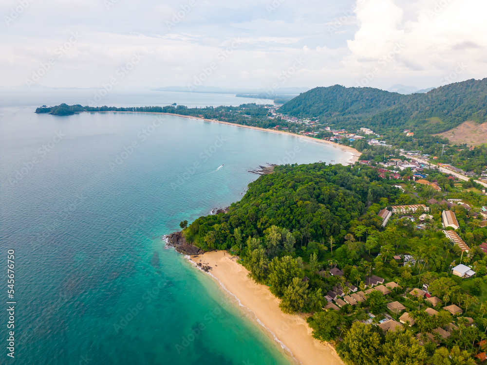 Aerial drone view of Koh Lanta island - the long beach. Famous tropical beach with white sand and turquoise ocean. The island mountains in background.