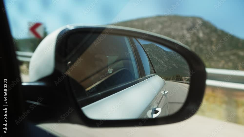 View of mountain range from side mirror of driving car on highway. View of mountain range from side mirror of driving car on highway.