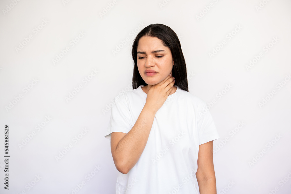 Portrait of displeased young woman touching her throat over white background. Caucasian lady wearing white T-shirt suffering from tonsillitis. Pulmonary diseases concept Portrait of displeased young woman touching her throat over white background. Caucasian lady wearing white T-shirt suffering from tonsillitis. Pulmonary diseases concept