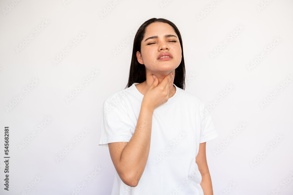 Portrait of sick young woman touching sore throat over white background. Caucasian lady wearing white T-shirt suffering from angina. Pulmonary diseases concept Portrait of sick young woman touching sore throat over white background. Caucasian lady wearing white T-shirt suffering from angina. Pulmonary diseases concept