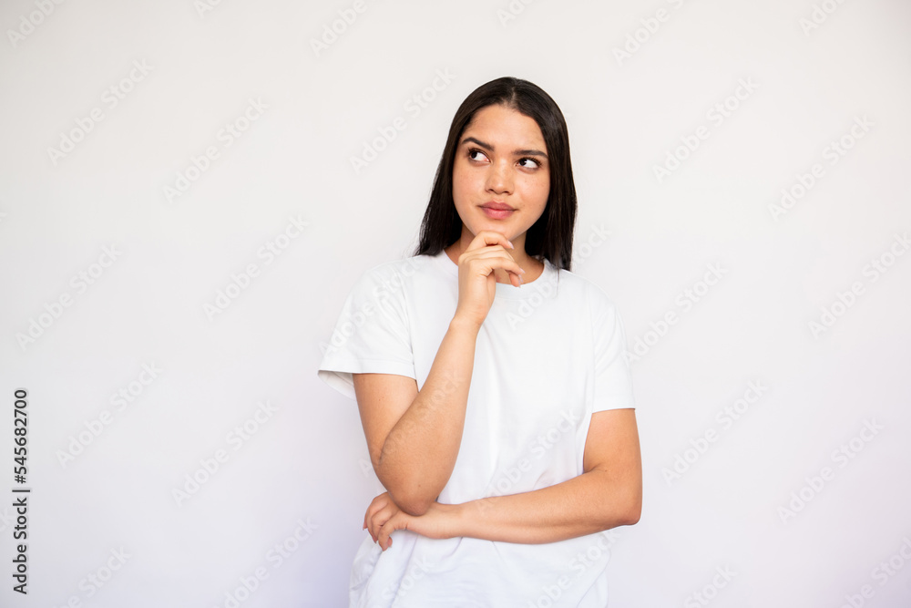 Portrait of pensive young woman looking away on white background. Caucasian lady wearing white T-shirt dreaming or thinking. Planning concept Portrait of pensive young woman looking away on white background. Caucasian lady wearing white T-shirt dreaming or thinking. Planning concept