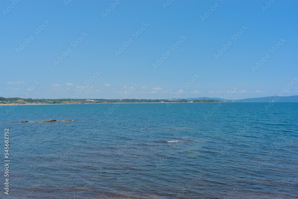 Clear water in the sea, blue sky, hills on a bright sunny day. Calm summer vacation landscape