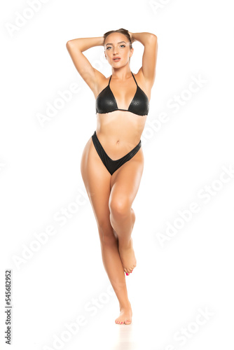 Beautiful young woman in black bikini on a white background. Front view