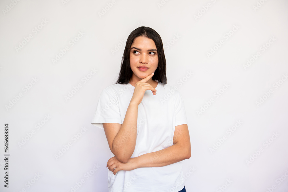 Portrait of thoughtful young woman looking away and thinking. Caucasian lady wearing white T-shirt posing with hand on chin over white background. Planning concept Portrait of thoughtful young woman looking away and thinking. Caucasian lady wearing white T-shirt posing with hand on chin over white background. Planning concept