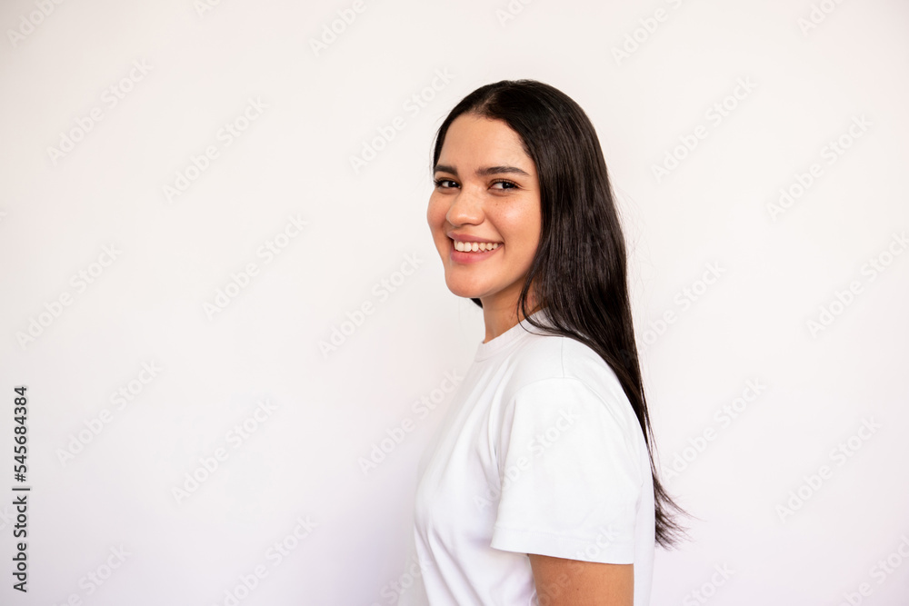 Portrait of candid young woman looking at camera and smiling over white background. Caucasian lady wearing white T-shirt posing in studio. Female beauty concept Portrait of candid young woman looking at camera and smiling over white background. Caucasian lady wearing white T-shirt posing in studio. Female beauty concept