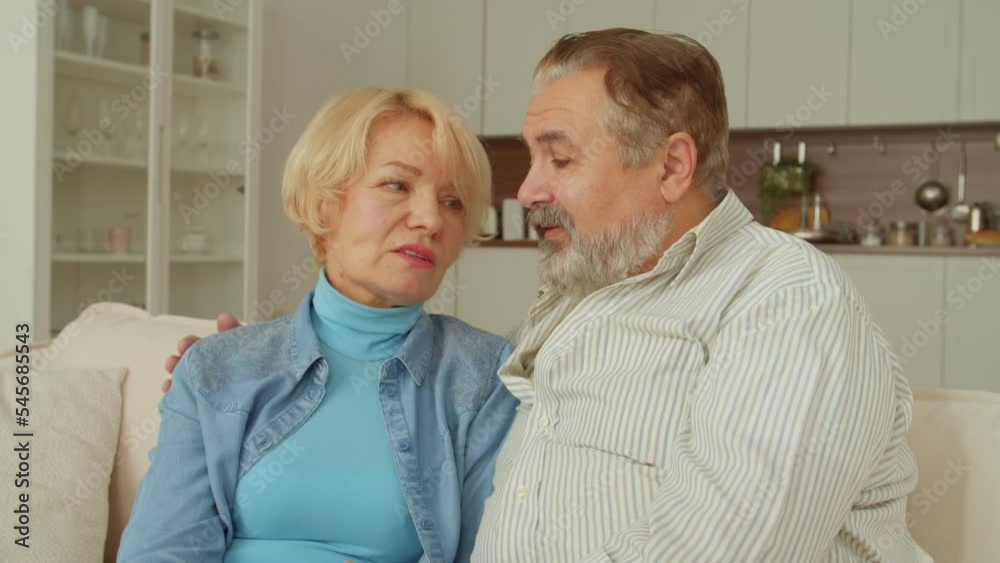 Portrait of affectionate pretty senior woman and handsome mature man sitting on couch, talking and bonding, hugging , expressing happiness and togetherness while retired couple enjoying leisure indoor Portrait of affectionate pretty senior woman and handsome mature man sitting on couch, talking and bonding, hugging , expressing happiness and togetherness while retired couple enjoying leisure indoor