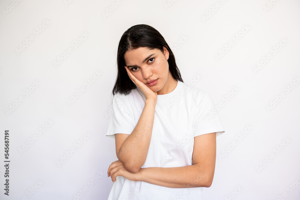 Portrait of bored young woman leaning head on hand over white background. Caucasian lady wearing white T-shirt looking at camera with indifference. Boredom concept Portrait of bored young woman leaning head on hand over white background. Caucasian lady wearing white T-shirt looking at camera with indifference. Boredom concept