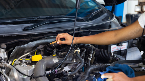 African female auto mechanic worker checking oil level in car engine at Car Service station. Car maintenance and auto service garage concept.