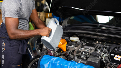 Pouring oil to car engine. Closue up male mechanic hand working and service in Car Service station