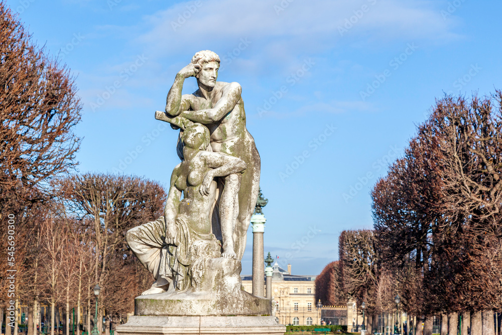 Fototapeta premium Statue of a standing man resting his arm above the head of a seated woman, at the Jardin des Grands Explorateurs Marco Polo et Cavelier de la Salle, in Odeon district in Paris, France, during winter.