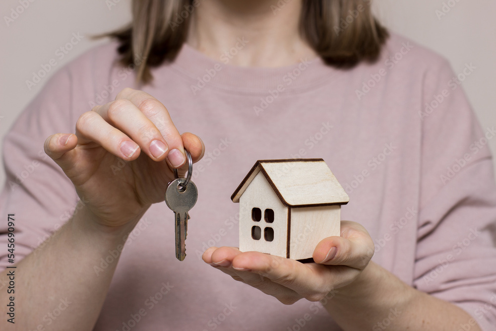 Girl holding a house made of wood and keys Girl holding a house made of wood and keys
