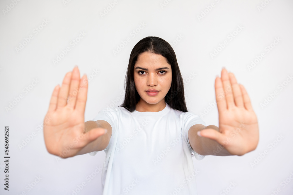 Portrait of serious young woman making denial gesture over white background. Caucasian lady wearing white T-shirt showing restriction sign. Forbiddance and restriction concept Portrait of serious young woman making denial gesture over white background. Caucasian lady wearing white T-shirt showing restriction sign. Forbiddance and restriction concept
