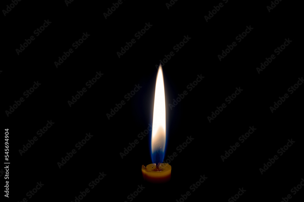 Flame from a burning thin candle. Candle flame on a black background. Burning candle. The candle burns in the dark Flame from a burning thin candle. Candle flame on a black background. Burning candle. The candle burns in the dark