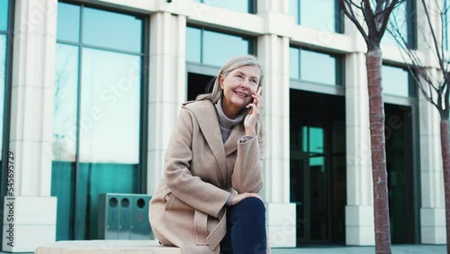 Wallpaper Mural Senior beautiful happy grey-haired woman sitting outside talking on phone communicating. Elegant stylish talkative mature female speaking chitchatting on fresh air wearing coat outside of office. Torontodigital.ca