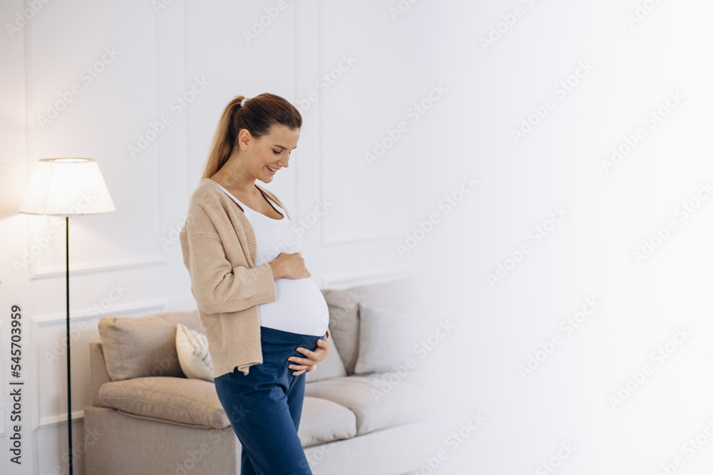Pregnant woman holding her belly aqt home Pregnant woman holding her belly aqt home