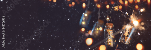 Garland of christmas lights on night sky. Illuminated string of lights in glass cylinders with golden bokeh and short depth of field Christmas banner with space for text. photo