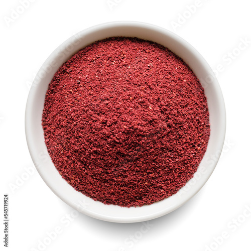 Dry ground sumac in white bowl isolated on white. Top view. photo