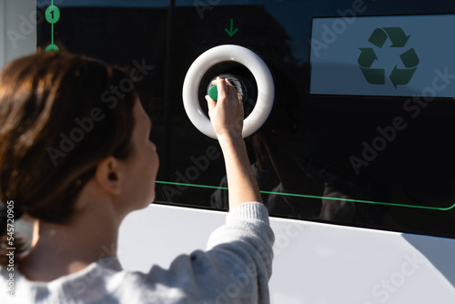 Woman uses a self service machine to receive used plastic bottles and cans on a city street photo