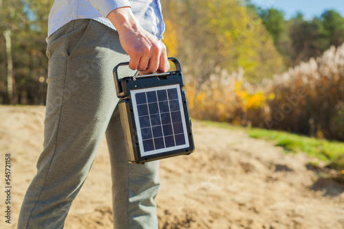The guy is carrying a portable solar charging station in his hands. Eco-friendly energy for camping and outdoor recreation. Solar panel with battery photo