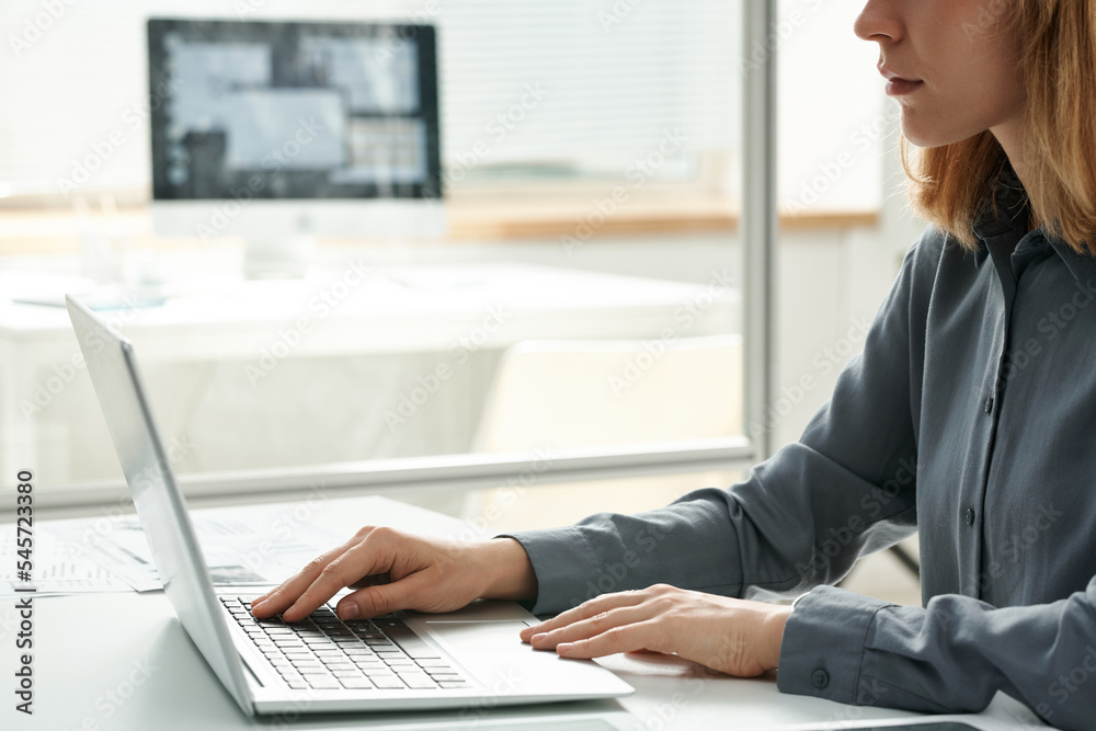 Close-up of young office worker typing on laptop while working at her workplace at office Close-up of young office worker typing on laptop while working at her workplace at office