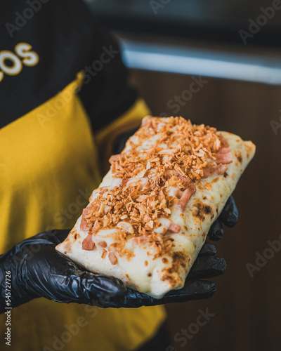 Tacos gratiné avec des onion crisps tenu dans les main d'un employé d'une chaine de fast food de french tacos photo