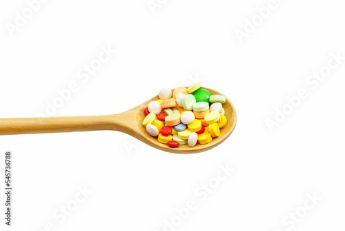 Closeup of various pills on wooden spoon isolated in white background