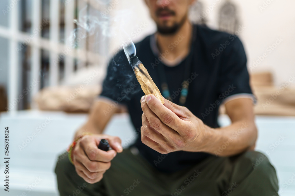 Man holding burning Palo Santo on light background Man holding burning Palo Santo on light background