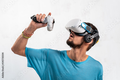 Young man using virtual reality headset on light background