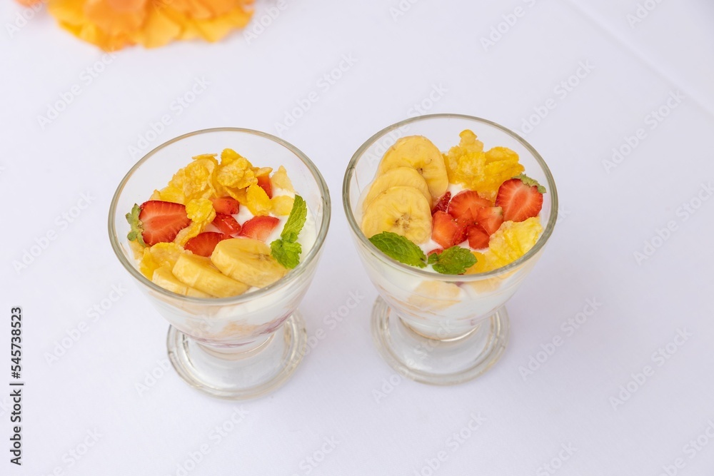 Top closeup of desserts in glass small bowls with fruits and yogurt on the white background Top closeup of desserts in glass small bowls with fruits and yogurt on the white background
