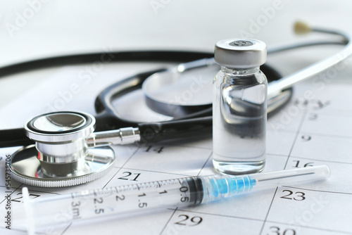 Konstfotografi A medical syringe needle with plain unmarked vial of medicine laying on a calendar page with a stethoscope