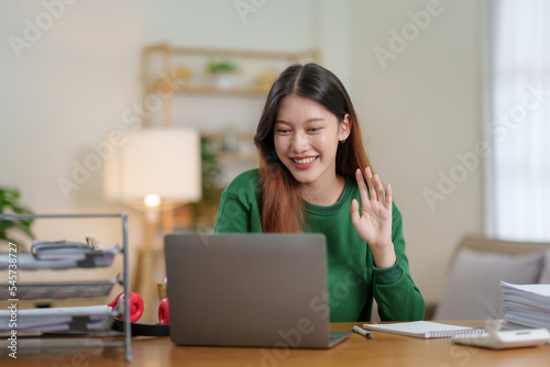 Beautiful young Asian business woman sit on a laptop video conference to discuss work and ongoing business. © amnaj