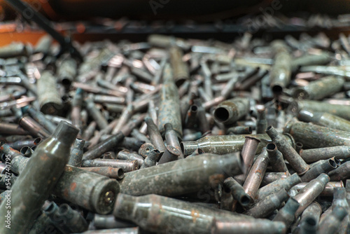 A lot of used old, rusty brass cartridge cases. Empty carbine or rifle cartridges. Background of brass ammunition cartridges to illustrate armed conflict, war or shooting.