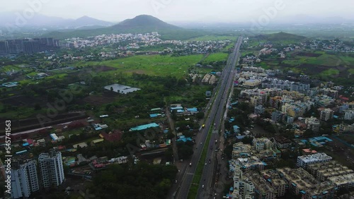 Aerial shot of a highway surrounded by meadow and residential buildings photo