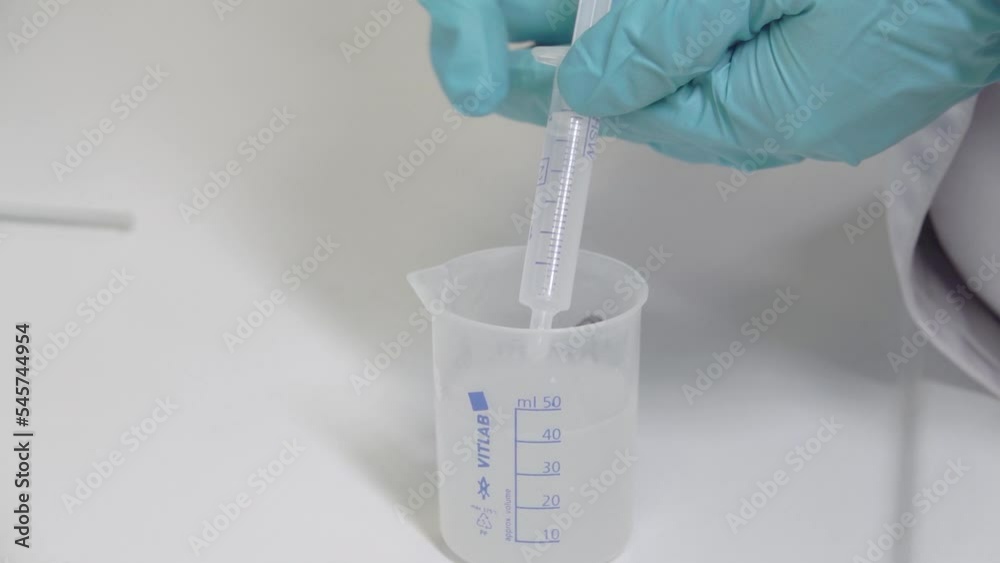 A scientist drips a chemical solution into a test tube in a laboratory experiment. chemical and oil concept. hd A scientist drips a chemical solution into a test tube in a laboratory experiment. chemical and oil concept. hd