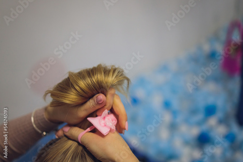 Top view selective focus on hands of mother doing braid on her daughter s hair. photo