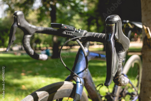 Details of the handlebar, brake levers and brake cable of a pro bike in the park in a sunny day