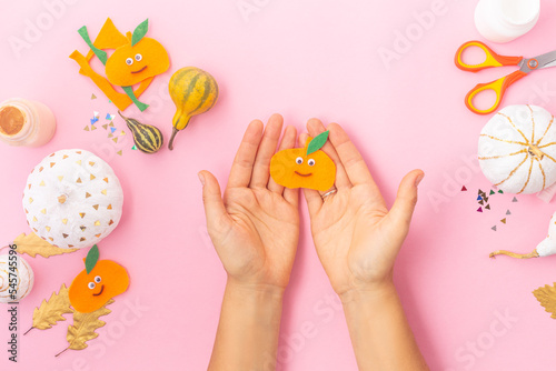 Autumn concept craft for kids, felt pumpkins with eyes and decorated pumpkins white and gold leaves woman hands