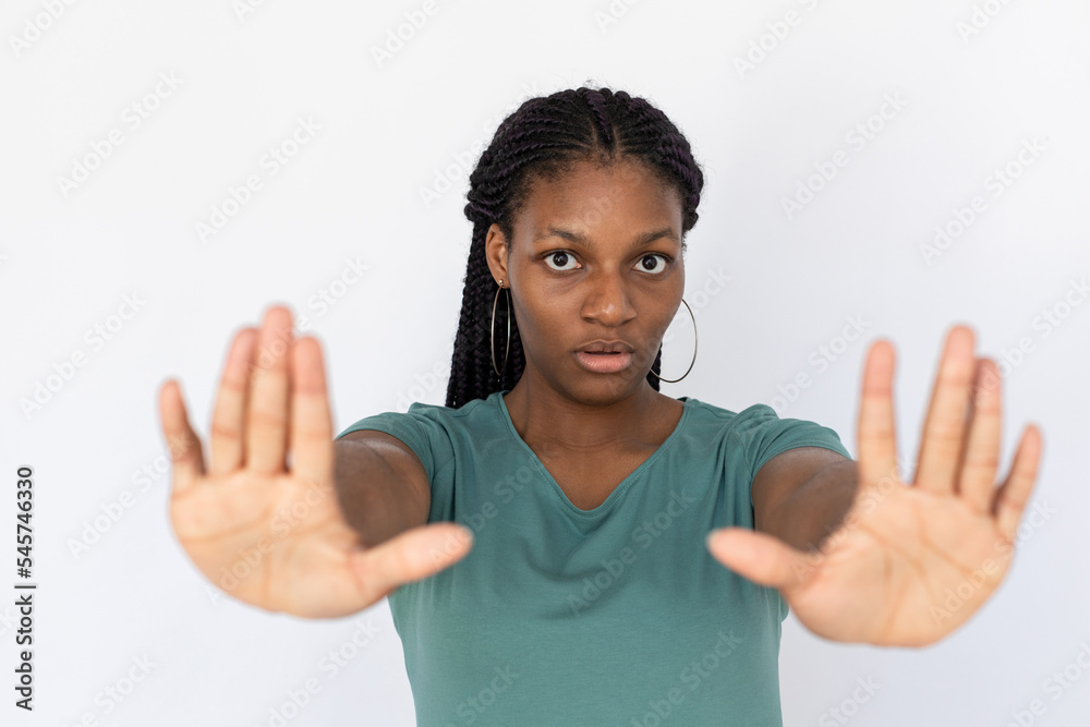 Slightly surprised woman showing stop gesture. Young female model in turquoise T-shirt stopping someone. Portrait, studio shot, caution concept Slightly surprised woman showing stop gesture. Young female model in turquoise T-shirt stopping someone. Portrait, studio shot, caution concept