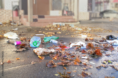 Plastic garbage scattered on the asphalt in the city among the autumn leaves. Environmental pollution. ecological problem