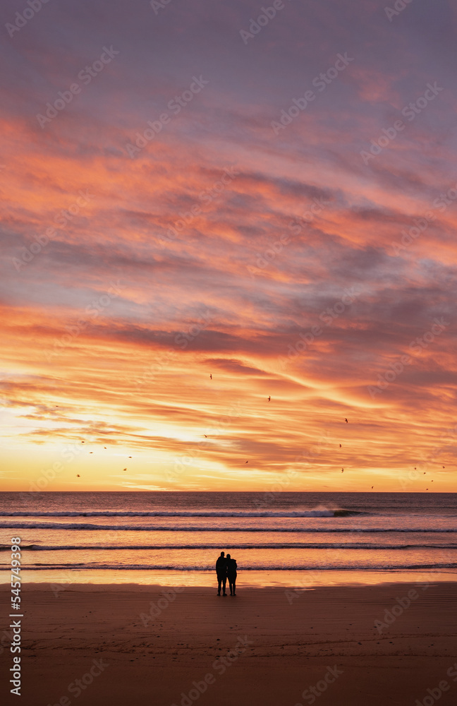 Couple silhouette embracing each other looking at dramatic sunrise at the beach. Couple silhouette embracing each other looking at dramatic sunrise at the beach.