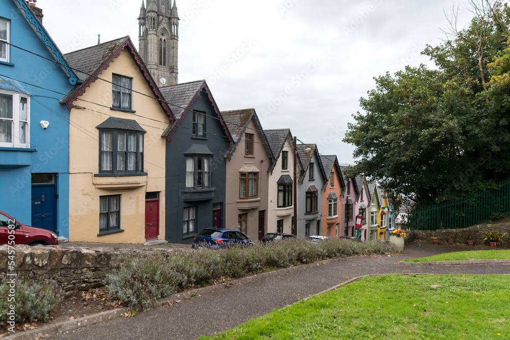 Colorful row of houses with towering cathedral in background in the port town of Cobh, County Cork, Ireland Colorful row of houses with towering cathedral in background in the port town of Cobh, County Cork, Ireland