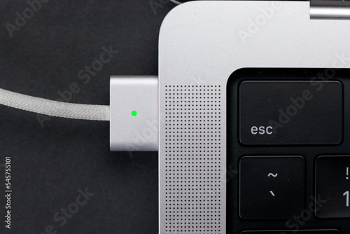 magsafe 3. Macbook pro 14 2022. magnetic charger charges laptop on black background. USB-C to MagSafe 3 Cable 