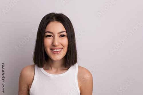 beauty portrait of a beautiful cheerful young oriental woman in a white T-shirt in the studio on a white wall. make-up artist and hairdresser hairdresser in a beauty salon.