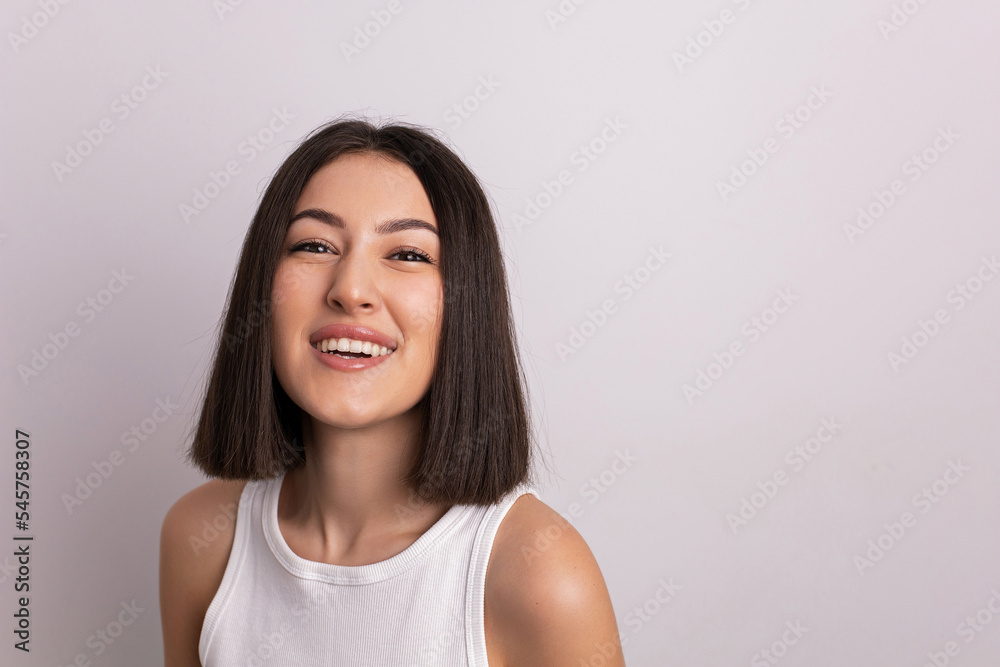 beauty portrait of a beautiful cheerful young oriental woman in a white T-shirt in the studio on a white wall. make-up artist and hairdresser hairdresser in a beauty salon. beauty portrait of a beautiful cheerful young oriental woman in a white T-shirt in the studio on a white wall. make-up artist and hairdresser hairdresser in a beauty salon.