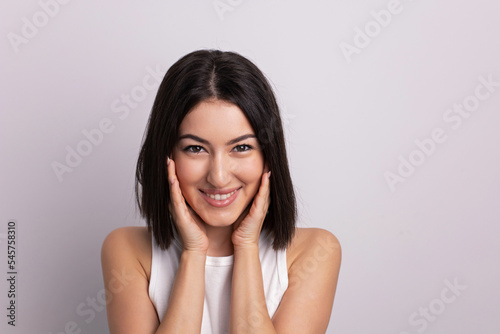 beauty portrait of a beautiful cheerful young oriental woman in a white T-shirt in the studio on a white wall. make-up artist and hairdresser hairdresser in a beauty salon.