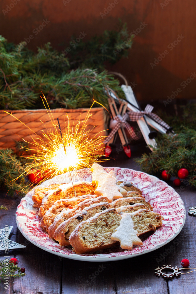 Christmas stollen with dried fruits, nuts and spices, Christmas decorations on a dark wooden background. Rustic style.