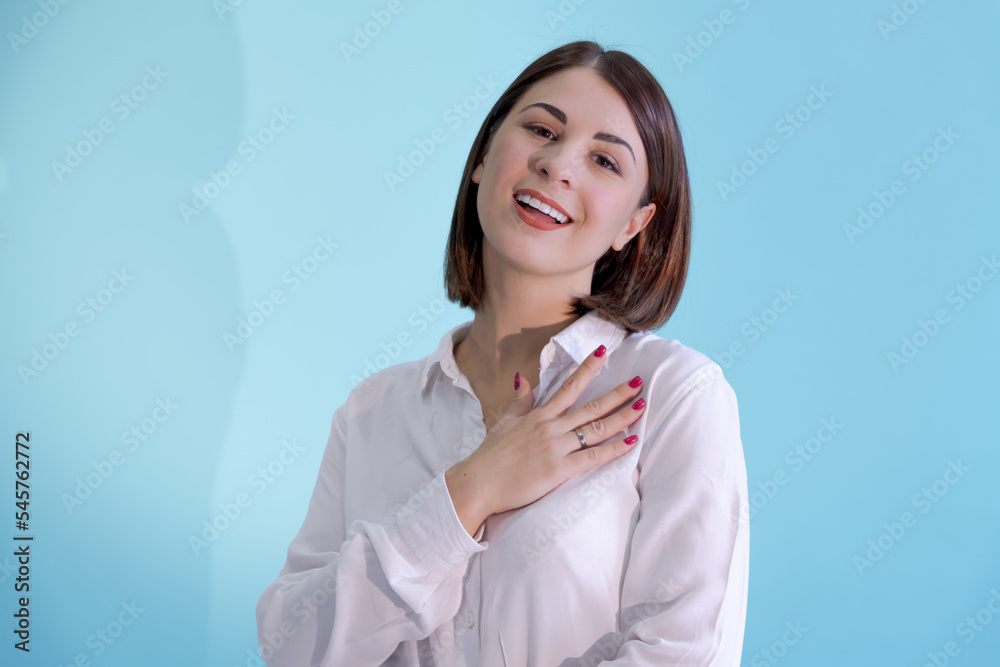 Portrait of beautiful smiling brunette caucasian woman wearing white shirt. Blue background. Selective focus. People theme. Portrait of beautiful smiling brunette caucasian woman wearing white shirt. Blue background. Selective focus. People theme.