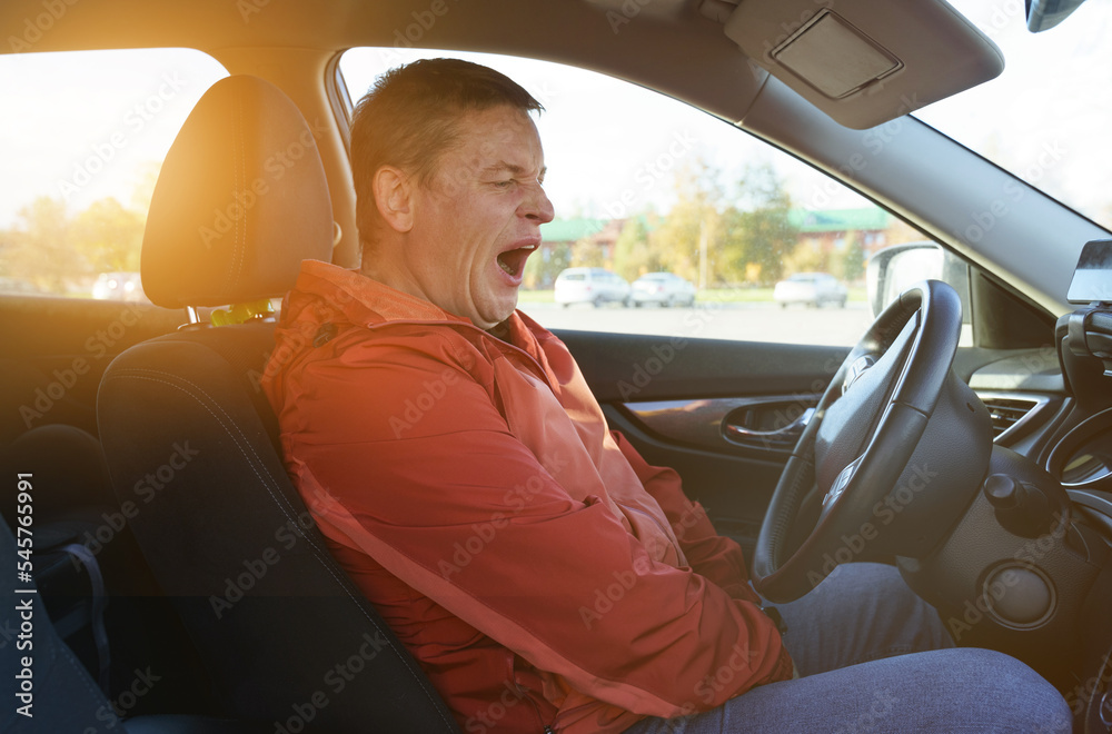 Tired driver man wants to sleep, yawns, opens his mouth.