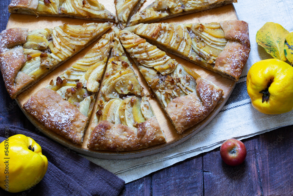Open pie stuffed with apples, quince and nuts on a wooden background. Rustic style.